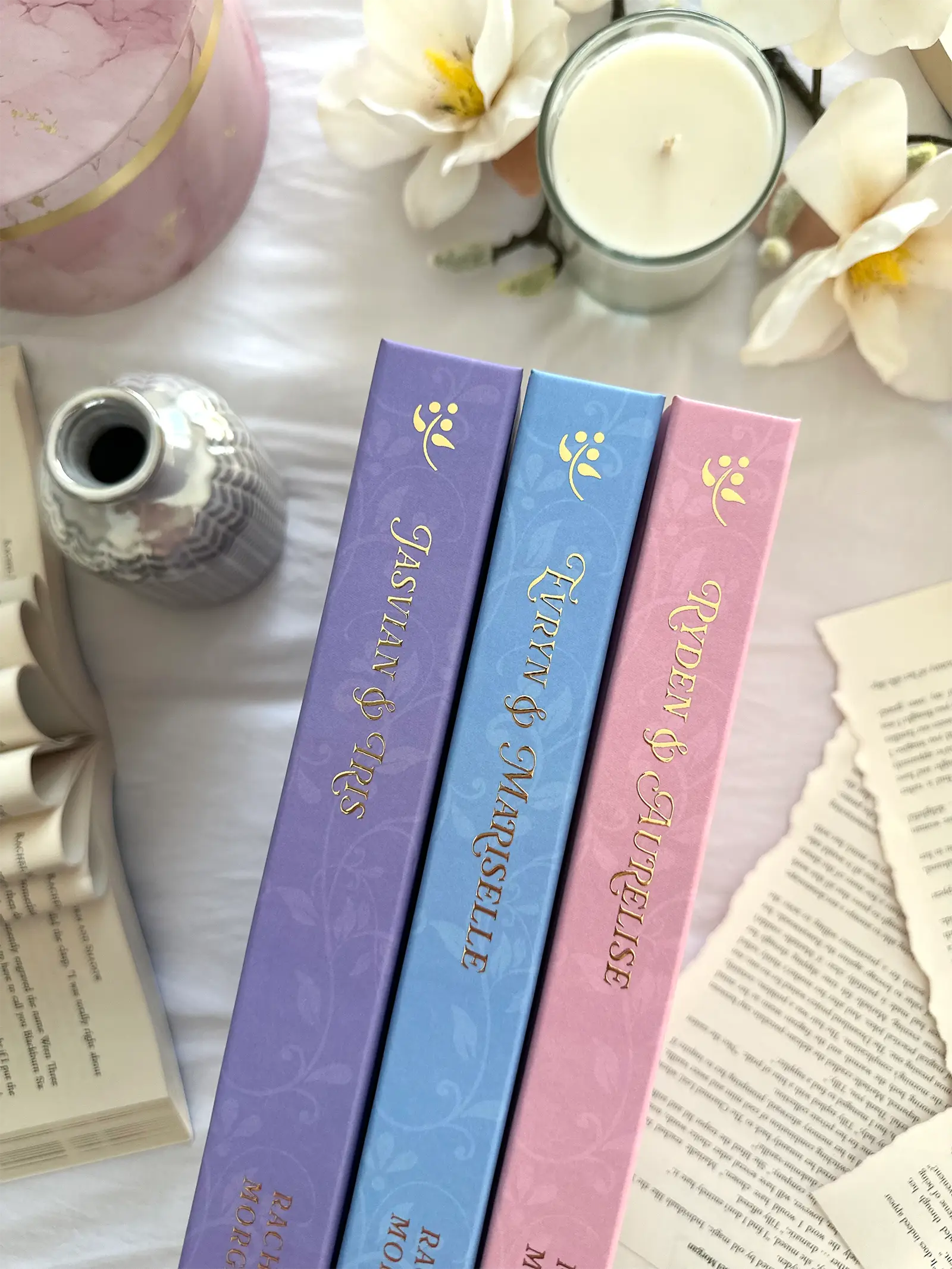 Gold foiled spines of the Charmed Leaf Legacy special edition hardbacks, featuring the name of the couple whose love story is told in each book.