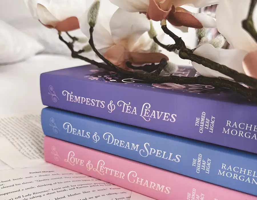 Charmed Leaf Legacy hardback books stacked on top of each other with flowers sitting on the top book